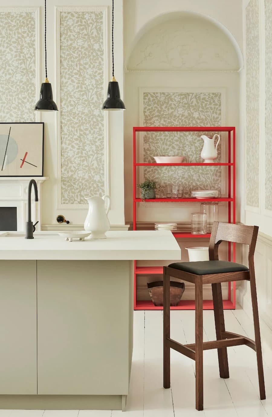 Cocina con la teoría del rojo inesperado. Cocina clásica moderna color beige, con taburete negro y repisa abierta metálica color rojo.