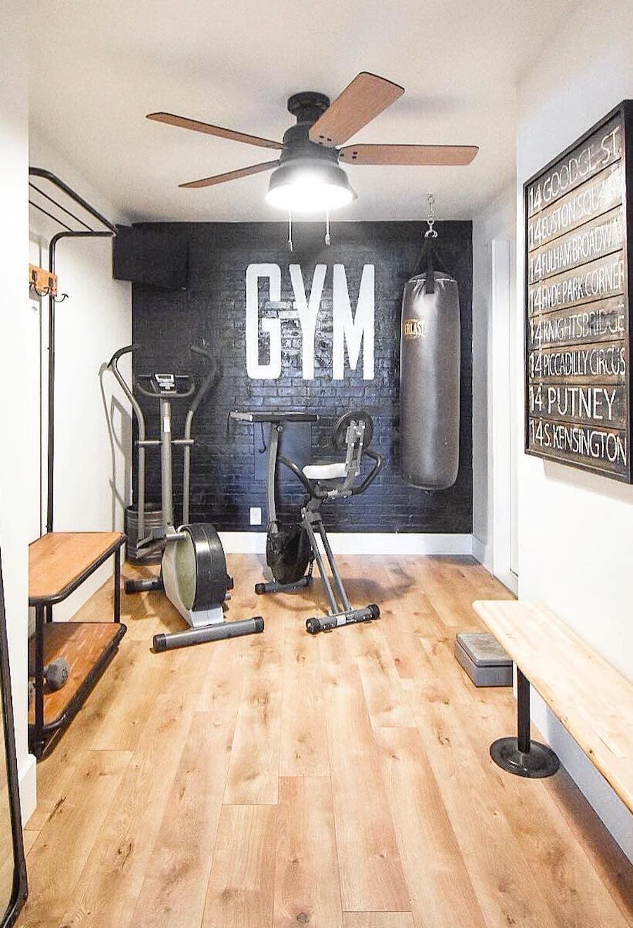 Gimnasio o lugar de entrenamiento en casa con muro negro, piso de madera y diferentes máquinas de ejercicios