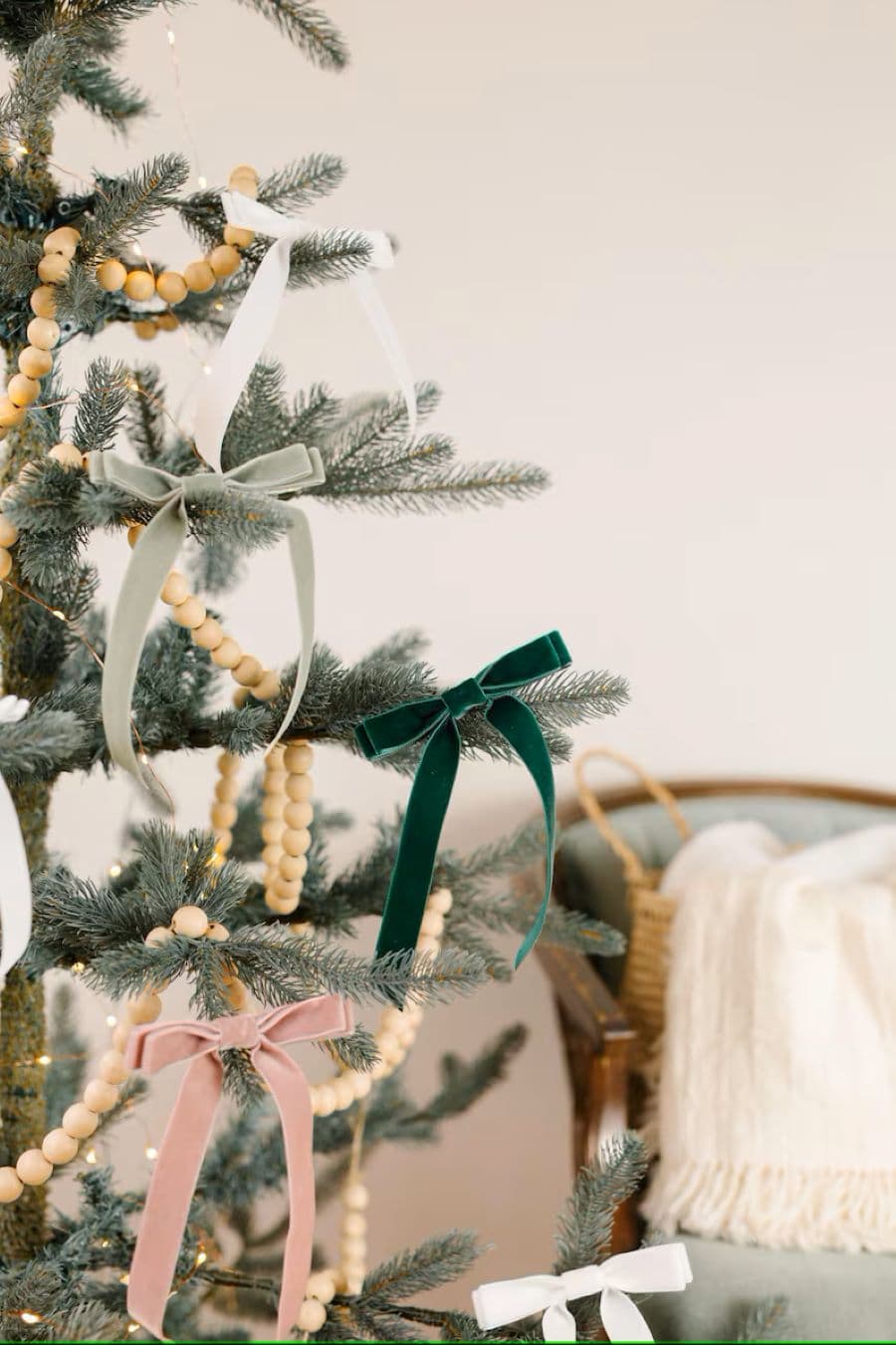 Detalle de árbol de Navidad con pequeños lazos de terciopelo en las puntas. Además tiene unas guirnaldas de pelotas de madera