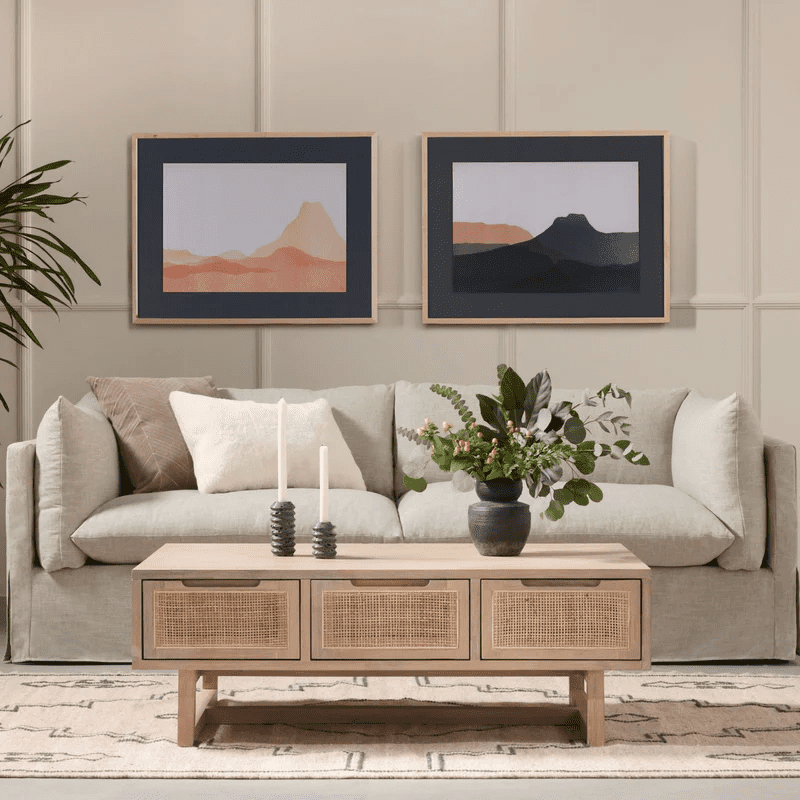 Living con un sofá de dos cuerpos blanco y, frente a él, una mesa de centro rectangular de madera con tres cajones de ratán.