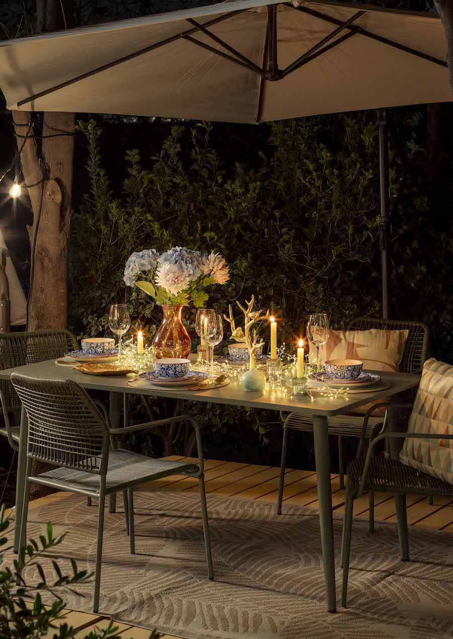 Deck con un comedor de terraza con velas que iluminan la mesa. El resto del ambiente está oscuro